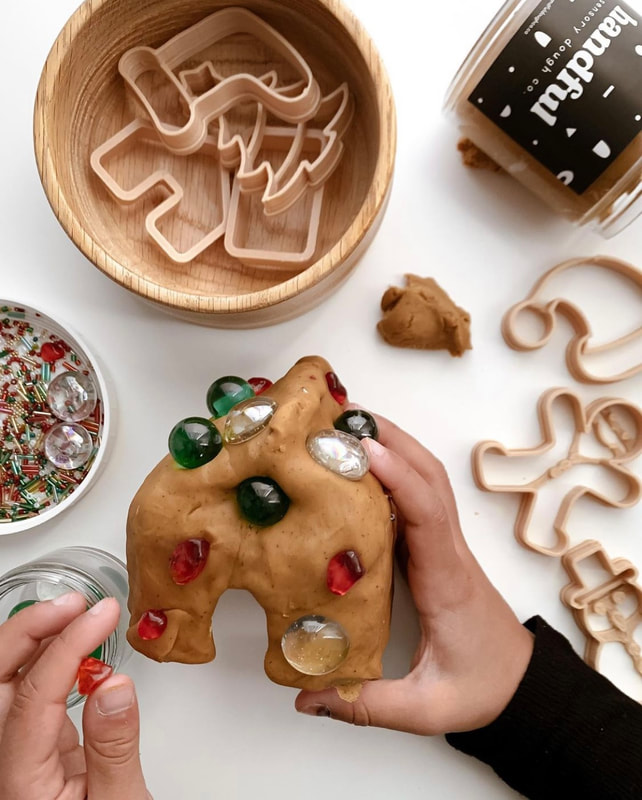 Childs hands playing with sensory dough and christmas themed cookie cutters