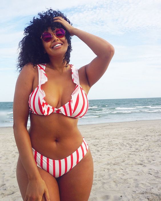 Tanned woman in sunglasses on the beach in a striped bikini