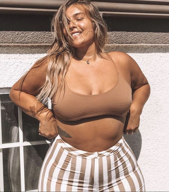 Tanned woman in striped shorts and beige crop top