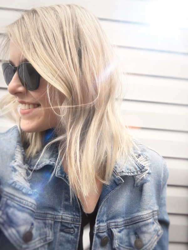 Bright medium length blonde hair on a smiling model in sunglasses giving cool-girl vibes.